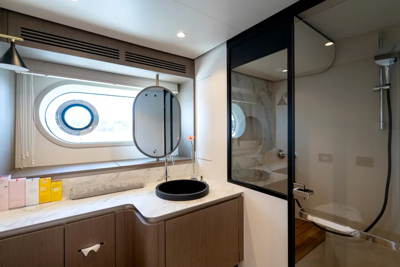 Olivia Yacht Photos Pics Luxurious bathroom on 2025 Azimut Magellano 60 yacht with modern fixtures and porthole window.