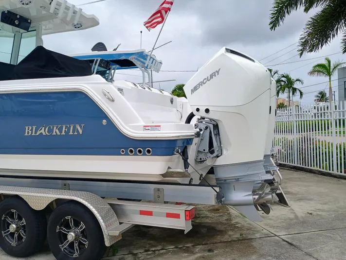  Yacht Photos Pics 2025 Blackfin 252 CC boat with Mercury engine on trailer, parked outdoors.
