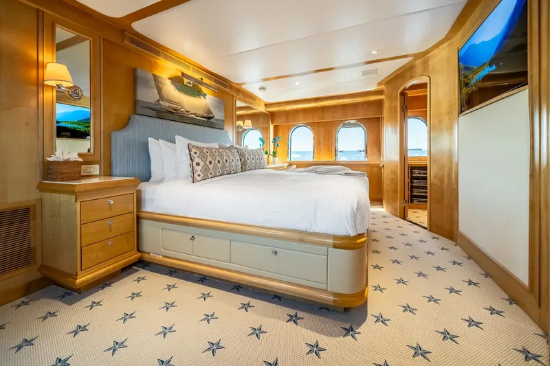 Destination Yacht Photos Pics Luxurious bedroom on 2007 MCP Tri-Deck yacht with elegant wood finishes and star-patterned carpet.