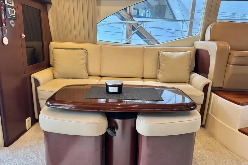 Barefoot Bliss Yacht Photos Pics Luxurious interior of 2007 Sea Ray 44 Sedan Bridge with beige seating and wooden table.