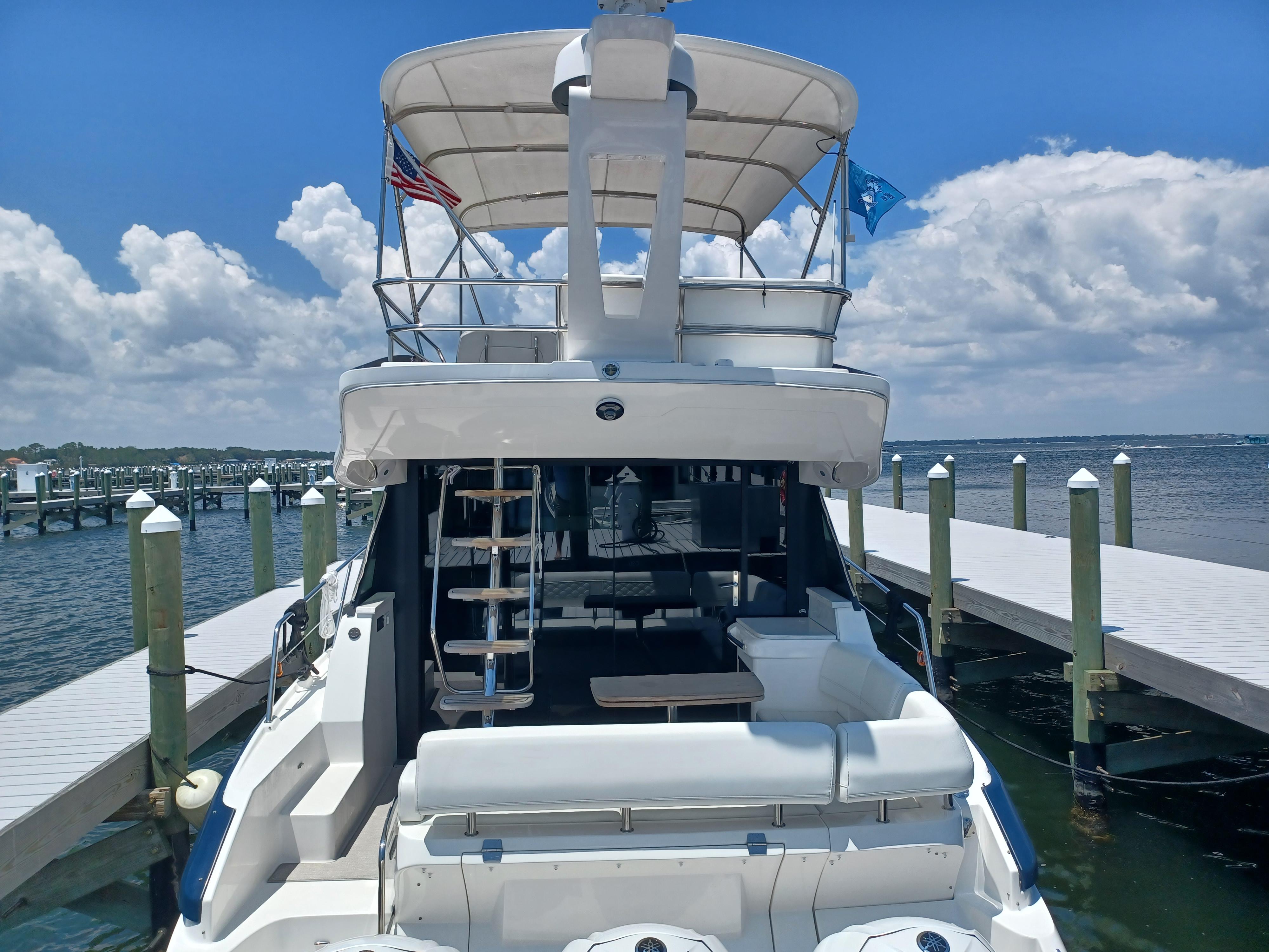 2023 Regal 42 FXO yacht docked at marina under clear blue sky.