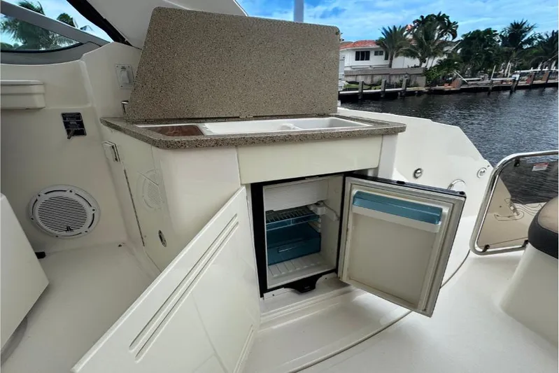  Yacht Photos Pics 2016 Sea Ray 350 Sundancer boat kitchenette with open mini-fridge and sink by the water.