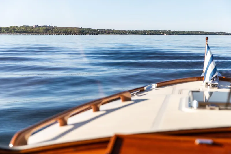 Leodes Yacht Photos Pics Hinckley Picnic Boat 34 S (2022) cruising on calm waters with scenic shoreline view.