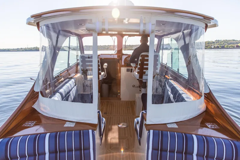 Leodes Yacht Photos Pics 2022 Hinckley Picnic Boat 34 S interior with striped seating on calm water.