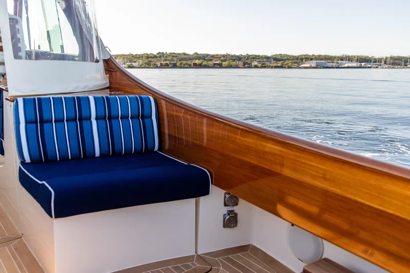 Leodes Yacht Photos Pics 2022 Hinckley Picnic Boat 34 S with blue-striped seating, wooden trim, and scenic water view.