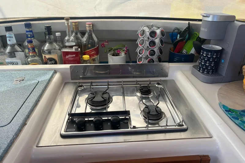 Sea Glass Yacht Photos Pics Galley kitchen in 2000 Fountaine Pajot Belize 43 with stove, bottles, and coffee maker.