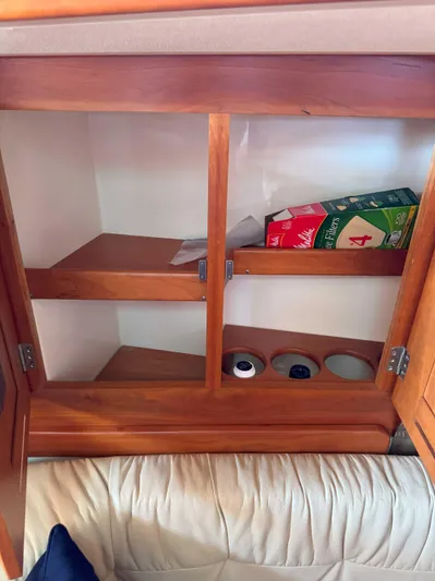 Side Aye Yacht Photos Pics Wooden cabinet interior with shelves, containing a box and small items, in a Tartan 3400 yacht.