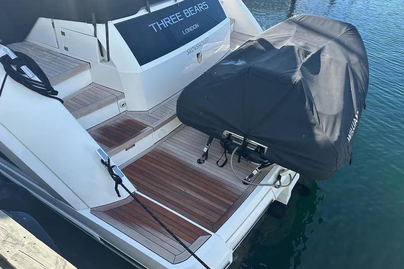 Three Bears Yacht Photos Pics 2012 Fairline Targa 58 yacht stern with covered equipment, docked on calm water.