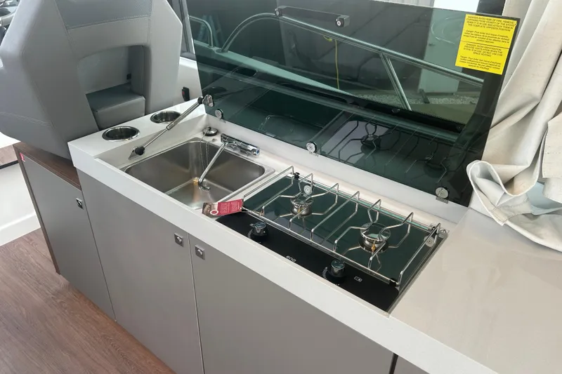  Yacht Photos Pics 2025 Beneteau Antares 11 Coupe kitchen with sink and dual-burner stove.