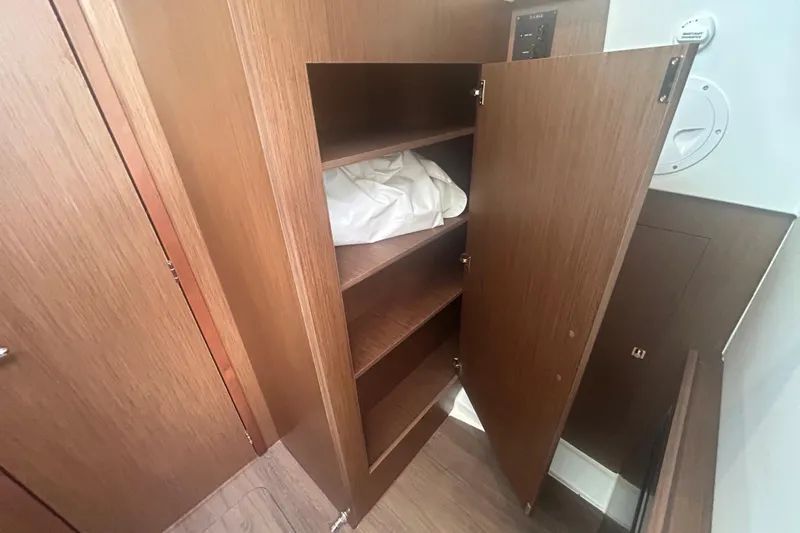  Yacht Photos Pics 2025 Beneteau Antares 11 Coupe interior wooden cabinet with open shelves.