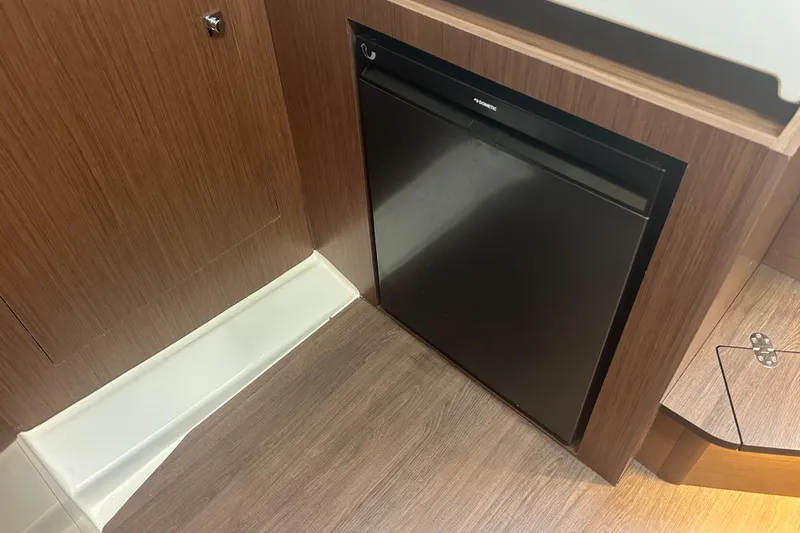  Yacht Photos Pics 2025 Beneteau Antares 11 Coupe interior with compact black refrigerator.