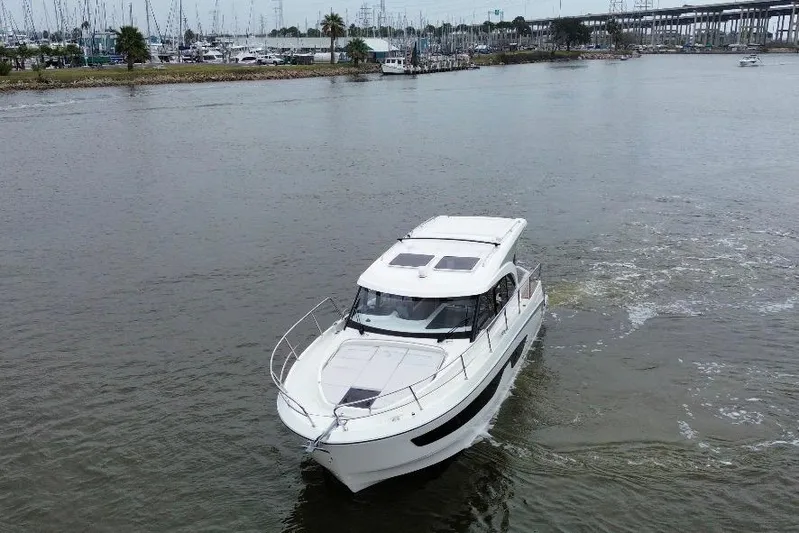  Yacht Photos Pics 2026 Beneteau Antares 11 Coupe cruising on a calm river near a marina.