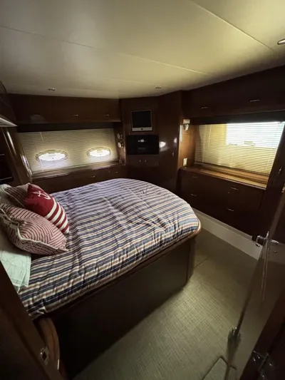 Odyssea II Yacht Photos Pics Interior of 2009 Carver 46 Motor Yacht bedroom with striped bedding and wooden cabinetry.