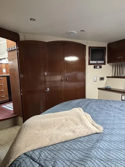Odyssea II Yacht Photos Pics Interior of 2009 Carver 46 Motor Yacht bedroom with wood cabinets and cozy bedding.