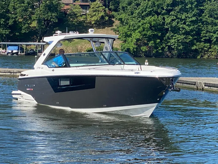  Yacht Photos Pics 2022 Monterey 378SS boat cruising on a lake near a dock, surrounded by trees.