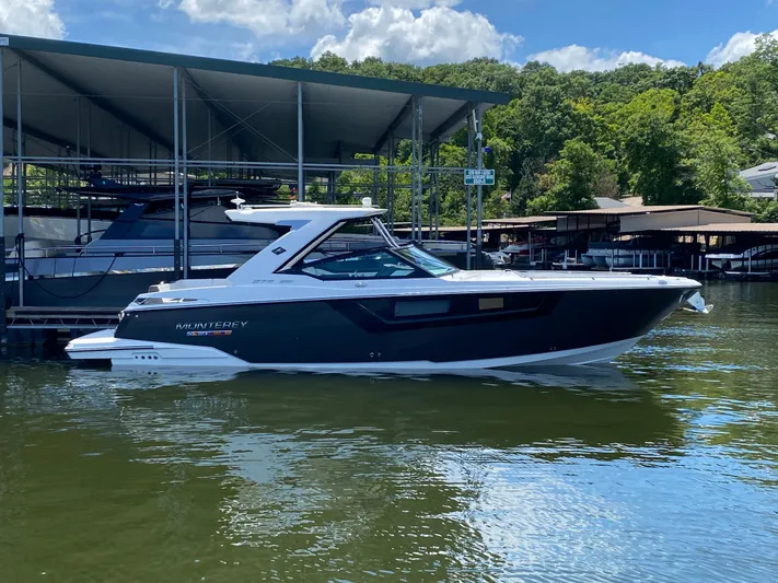  Yacht Photos Pics 2022 Monterey 378SS boat docked on a sunny day, surrounded by lush greenery.