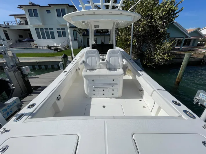  Yacht Photos Pics 2023 Regulator 31 boat interior with white seating and storage, docked near waterfront homes.