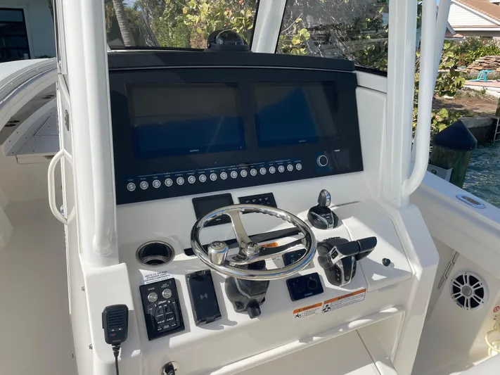  Yacht Photos Pics Control panel of a 2023 Regulator 31 boat with steering wheel and navigation screens.