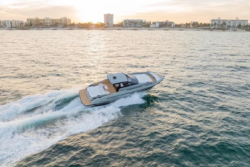  Yacht Photos Pics 2024 Rio Yachts Daytona 50 cruising at sunset near coastal city skyline.