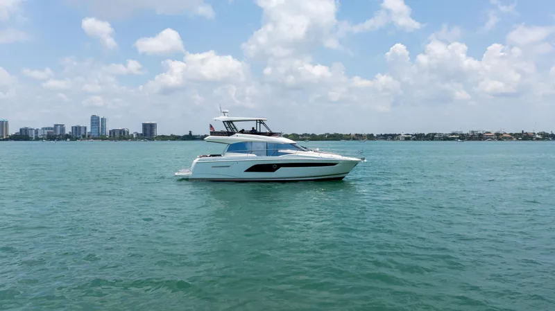 Motivated Seller Yacht Photos Pics 2019 Prestige 520 Flybridge yacht cruising on a sunny day with city skyline in the background.