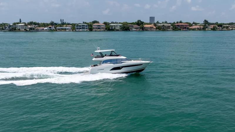 Motivated Seller Yacht Photos Pics 2019 Prestige 520 Flybridge yacht cruising on a sunny day near coastal homes.