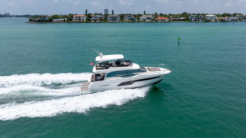 Motivated Seller Yacht Photos Pics 2019 Prestige 520 Flybridge yacht cruising on a sunny day near coastal homes.