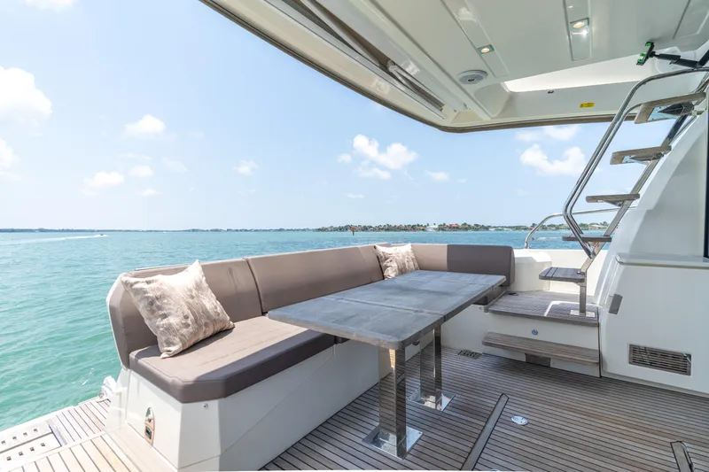 Motivated Seller Yacht Photos Pics Prestige 520 Flybridge 2019 yacht with outdoor seating and table, overlooking serene ocean waters.