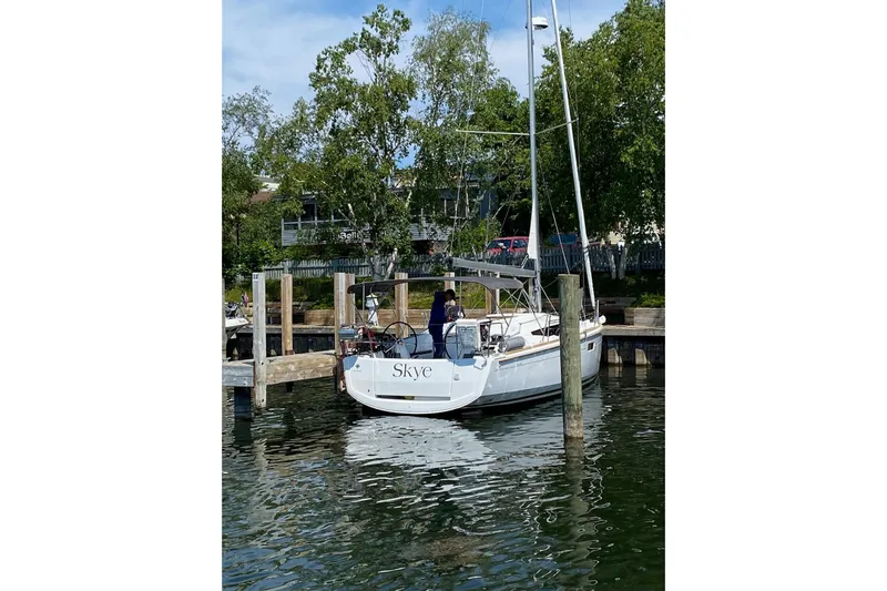  Yacht Photos Pics 2023 Jeanneau Sun Odyssey 349 sailboat docked, named "Skye," surrounded by trees and calm water.