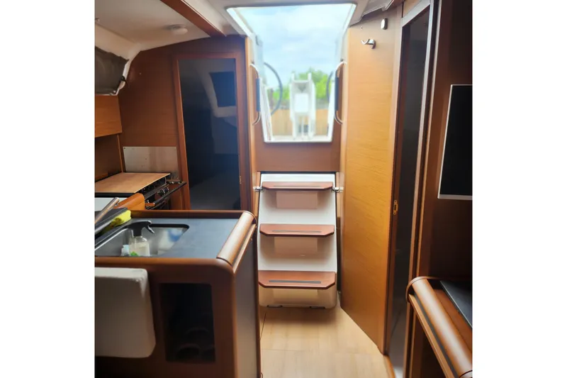 Yacht Photos Pics Interior of 2023 Jeanneau Sun Odyssey 349 sailboat, featuring modern kitchen and wooden cabinetry.