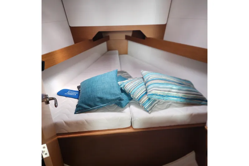  Yacht Photos Pics Cozy cabin interior of 2023 Jeanneau Sun Odyssey 349 with striped cushions.