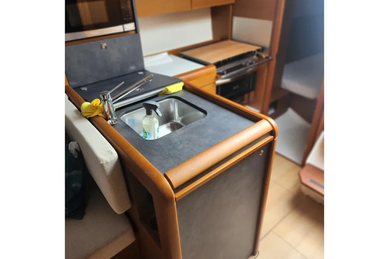  Yacht Photos Pics Compact kitchen area in 2023 Jeanneau Sun Odyssey 349 sailboat, featuring a sink and stove.
