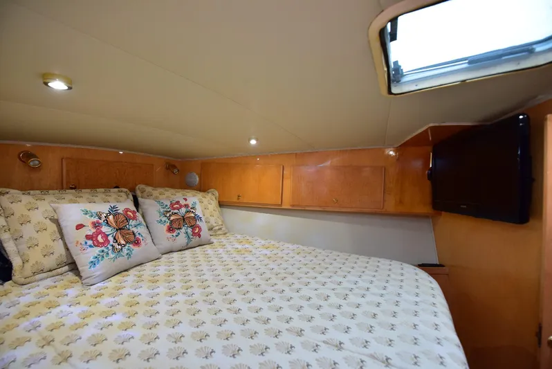 Next Chapter Yacht Photos Pics Cozy bedroom in 2004 Navigator Rival yacht with floral pillows and wooden cabinetry.