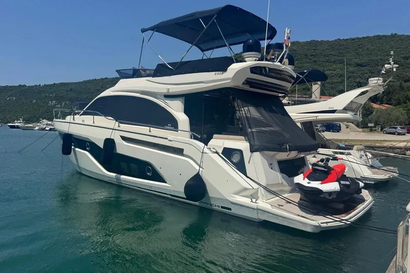  Yacht Photos Pics 2018 Cranchi E52 F yacht docked with jet ski on deck, scenic marina backdrop.