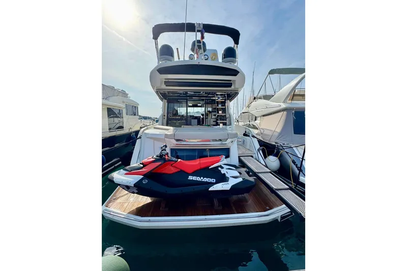  Yacht Photos Pics 2018 Cranchi E52 F yacht with a Sea-Doo jet ski on the deck, docked at a marina.