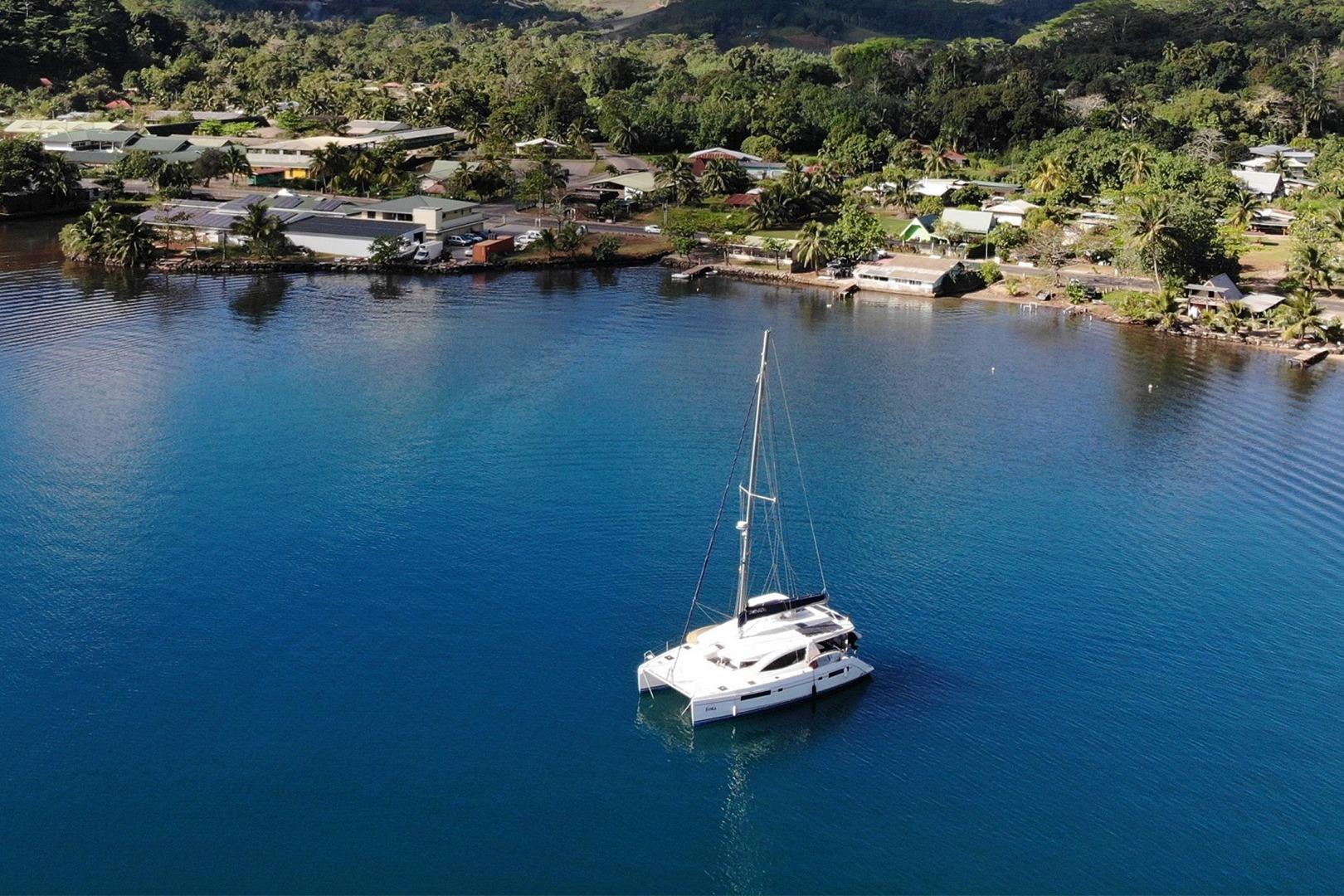 Sailboat Leopard 48 (2013) anchored in tranquil bay near lush coastal village.