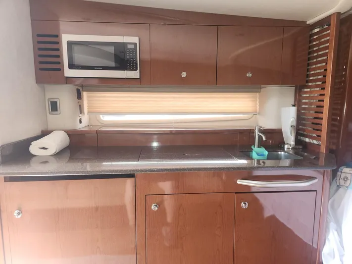  Yacht Photos Pics 2013 Sea Ray 370 Sundancer yacht kitchen with microwave, sink, and wooden cabinetry.