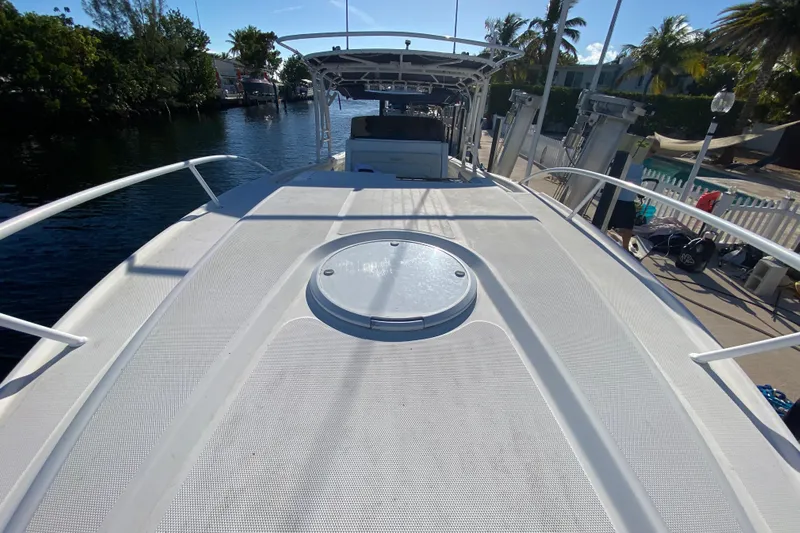  Yacht Photos Pics 2004 Deep Impact 36 DI boat deck with hatch, docked near palm trees and waterway.