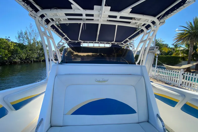  Yacht Photos Pics 2004 Deep Impact 36 DI boat with blue and white seating, docked near lush greenery.