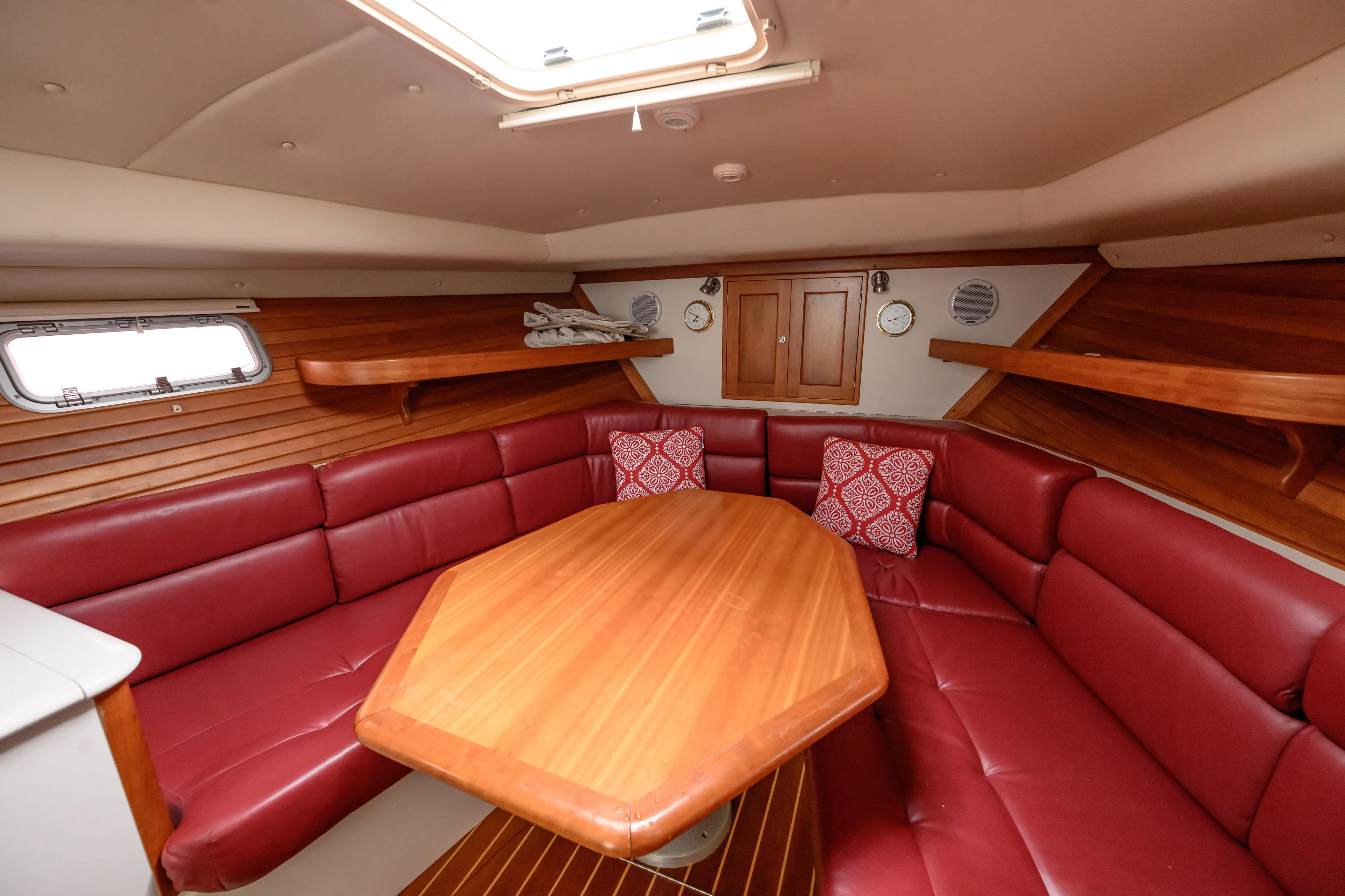 Staying Stoked Yacht Photos Pics Luxurious 2005 MJM 34z Downeast yacht interior with red leather seating and wooden table.