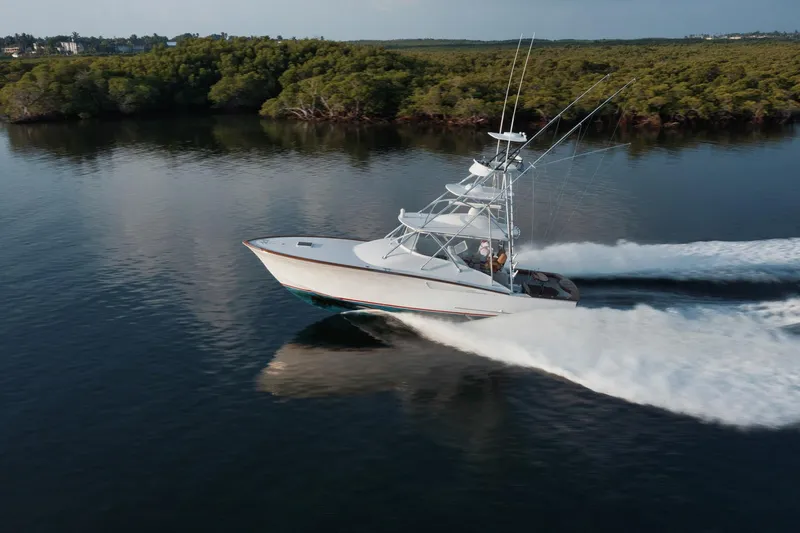 Dog House Yacht Photos Pics 2016 F&S Express boat cruising on calm water near lush green shoreline.