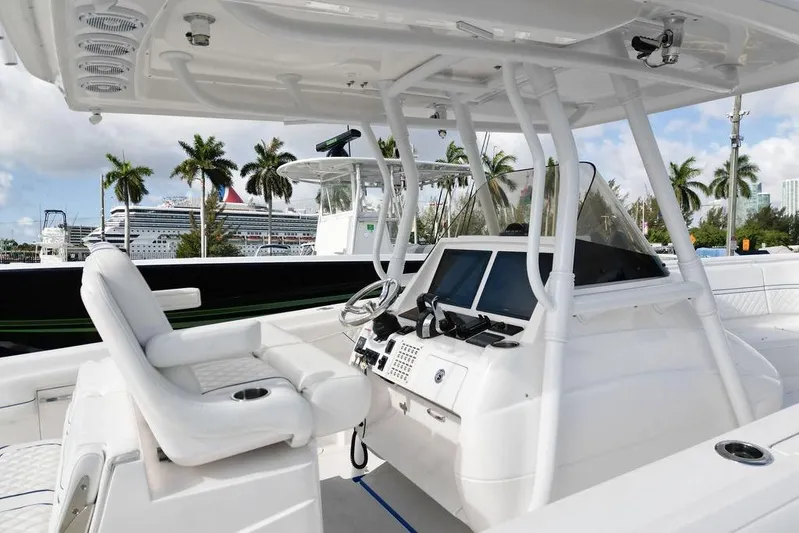  Yacht Photos Pics 2022 Intrepid 345 Nomad FE boat interior with helm, palm trees, and cruise ship in background.