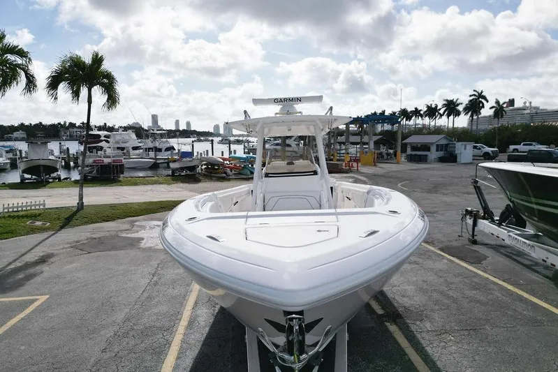  Yacht Photos Pics 2022 Intrepid 345 Nomad FE boat docked at a marina with palm trees and cloudy sky.
