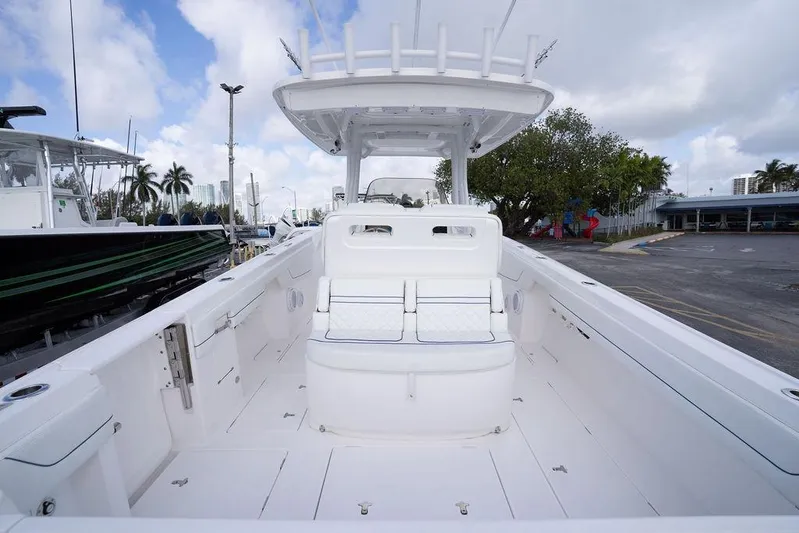  Yacht Photos Pics 2022 Intrepid 345 Nomad FE boat interior with seating and helm, docked under cloudy sky.