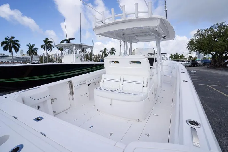  Yacht Photos Pics 2022 Intrepid 345 Nomad FE boat with spacious deck and seating, docked under a blue sky.