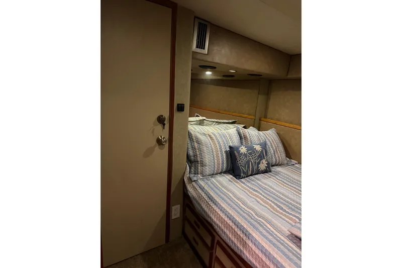 Unbelievable Yacht Photos Pics Cozy bedroom interior of 1984 Bertram 42 Convertible yacht with striped bedding and floral pillow.