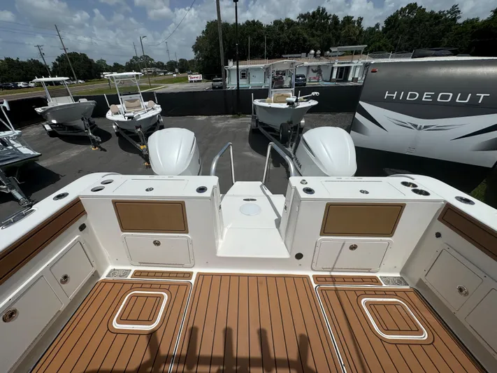  Yacht Photos Pics 2019 World Cat 3200 boat deck with wood finish, surrounded by other boats and a trailer.