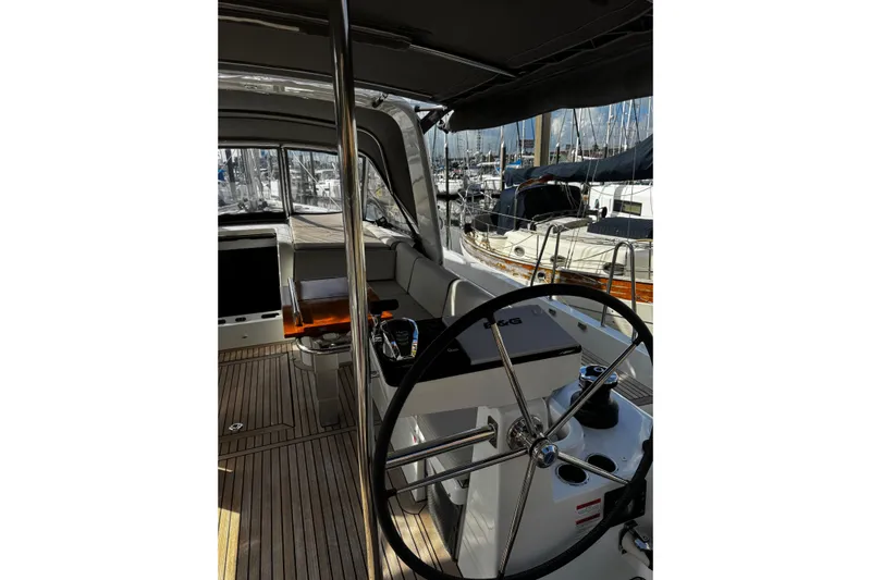 Sea Dawgs Yacht Photos Pics Cockpit view of 2021 Beneteau Oceanis Yacht 54 with steering wheel and marina background.