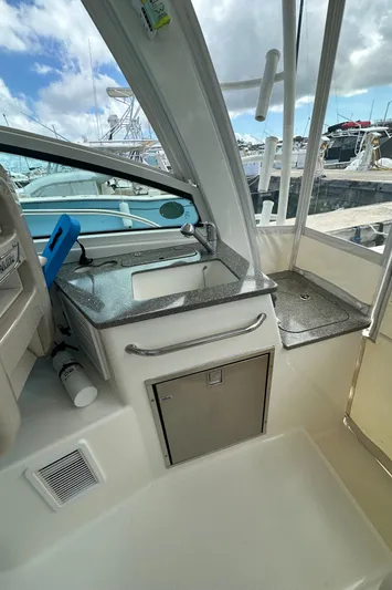  Yacht Photos Pics 2015 Boston Whaler 345 Conquest interior with sink and storage, docked under a cloudy sky.