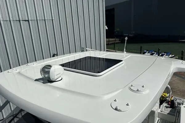 Keys Please! Yacht Photos Pics 2024 Jeanneau Leader 9.0 WA boat roof with hatch and radar, docked near a warehouse.