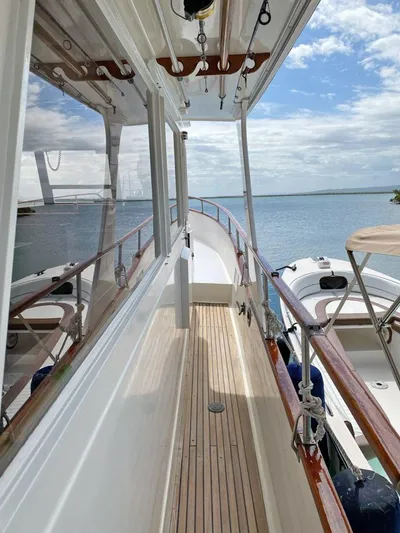  Yacht Photos Pics 1981 Grand Banks 42 Europa yacht with wooden deck, docked by calm waters under a partly cloudy sky.